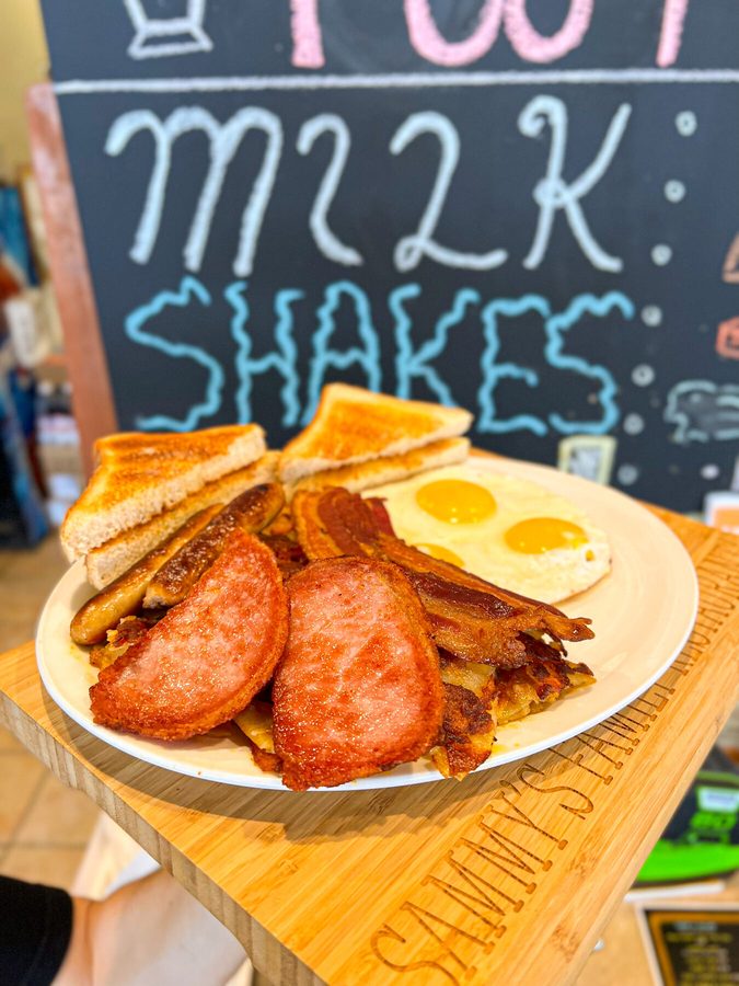 A loaded breakfast platter with peameal bacon, sausage, bacon, eggs, homefries and toast
