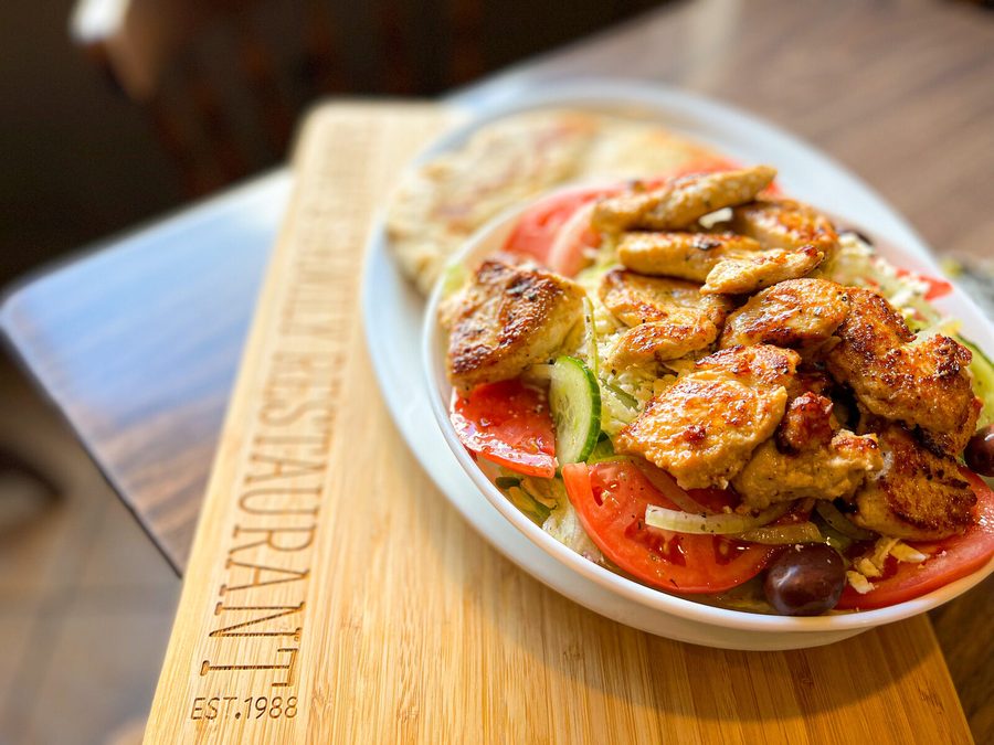 Grilled chicken over Greek salad with tomato, cucumber, feta, olives and warm pita