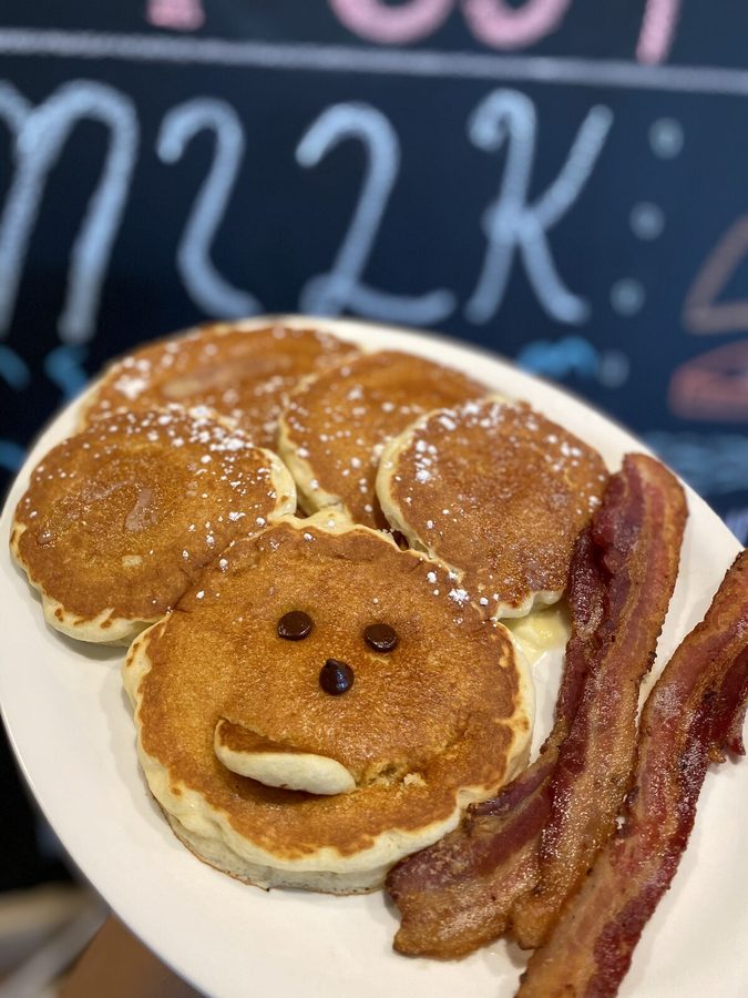 Kids Mickey Mouse pancake with chocolate chip face, served with bacon